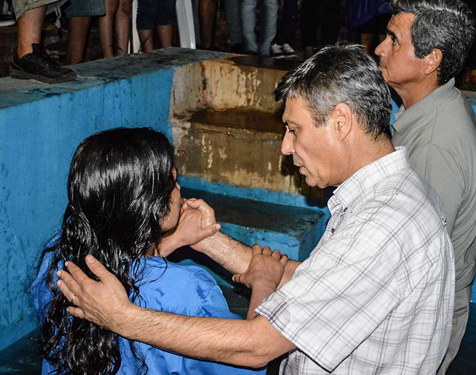 Paraguayan teenage girl baptized by Christian missionary in a concrete baptismal