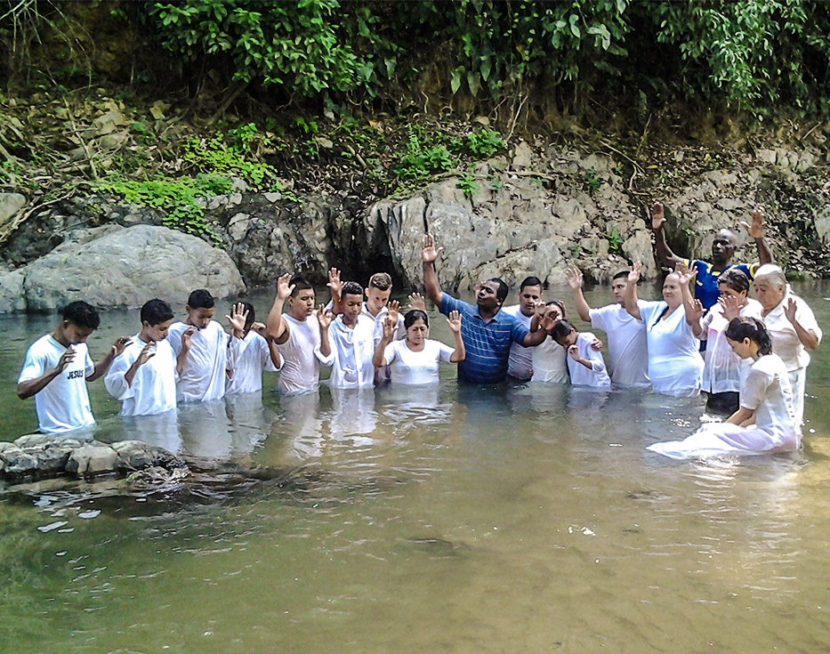 New Ecuadorian Christians in white shirts raising their hands after being baptized