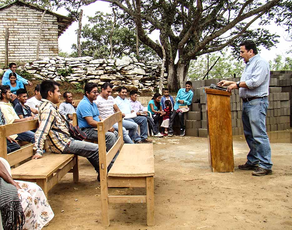 Christian missionary preaches outside to a group of Mexican people