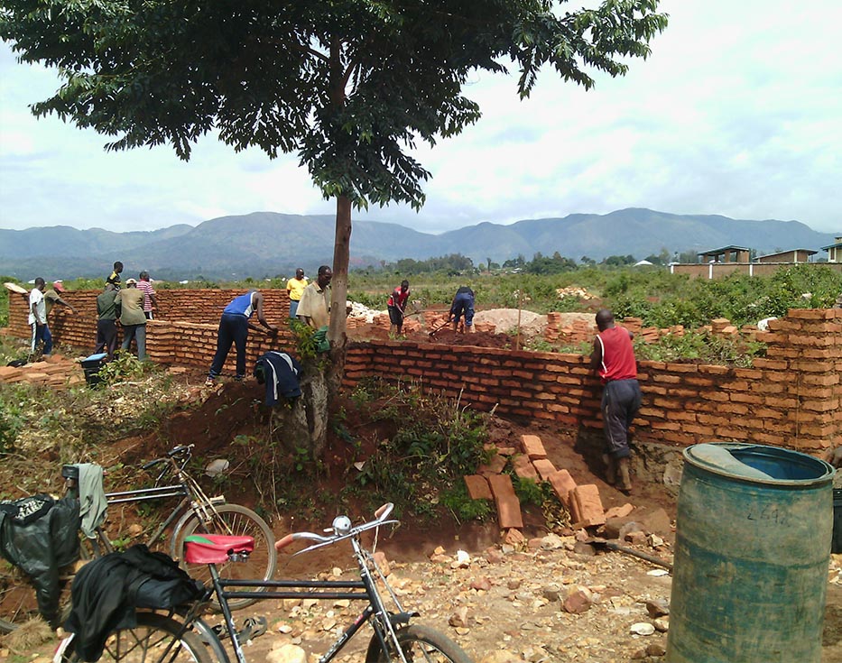 Burundian men work to build a wall with clay bricks