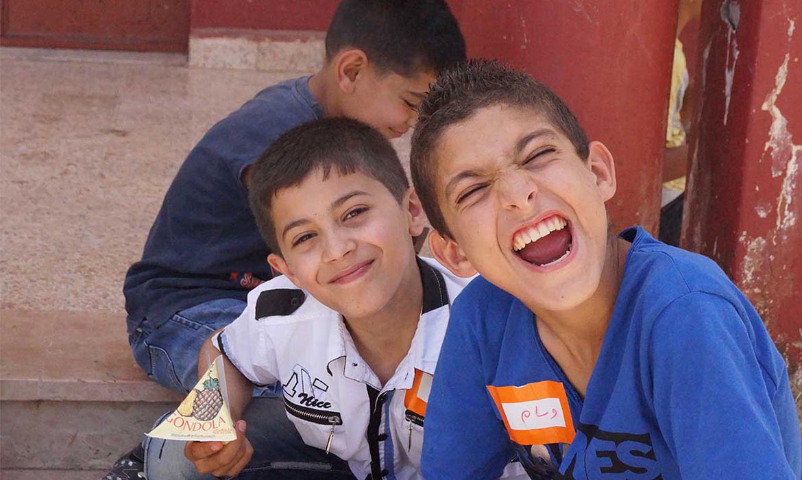 Middle Eastern school boys with big smiles while eating lunch outside