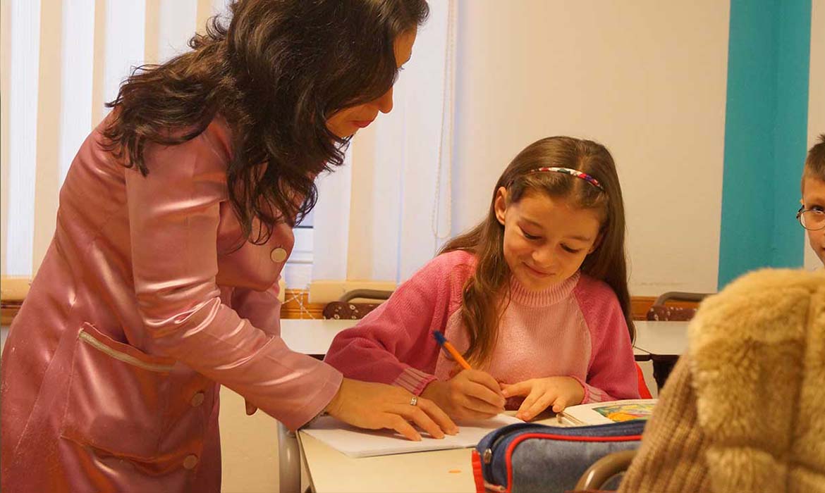 Christian woman helping to teach an Albanian girl how to write in English
