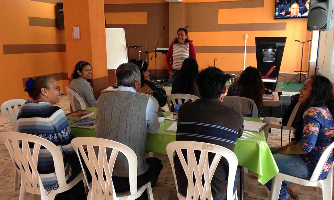 Mexican Christians sit at a table listening to a presentation on local missions