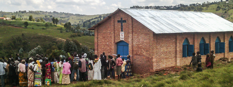 Burundian Christians stand in front of their church looking at the hillside
