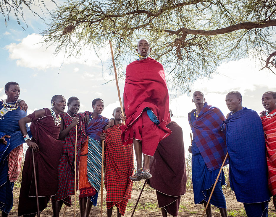 Man from the Maasai people in Tanzania jumps while others watch