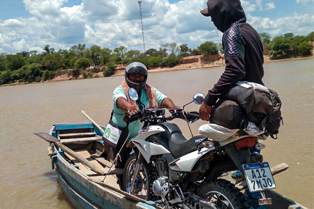Two Argentinian Christians in a wooden boat transporting a motorcycle from one side of the river to the other