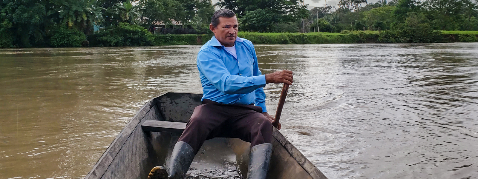 Brazilian Christian missionary paddles across a river in a wooden boat