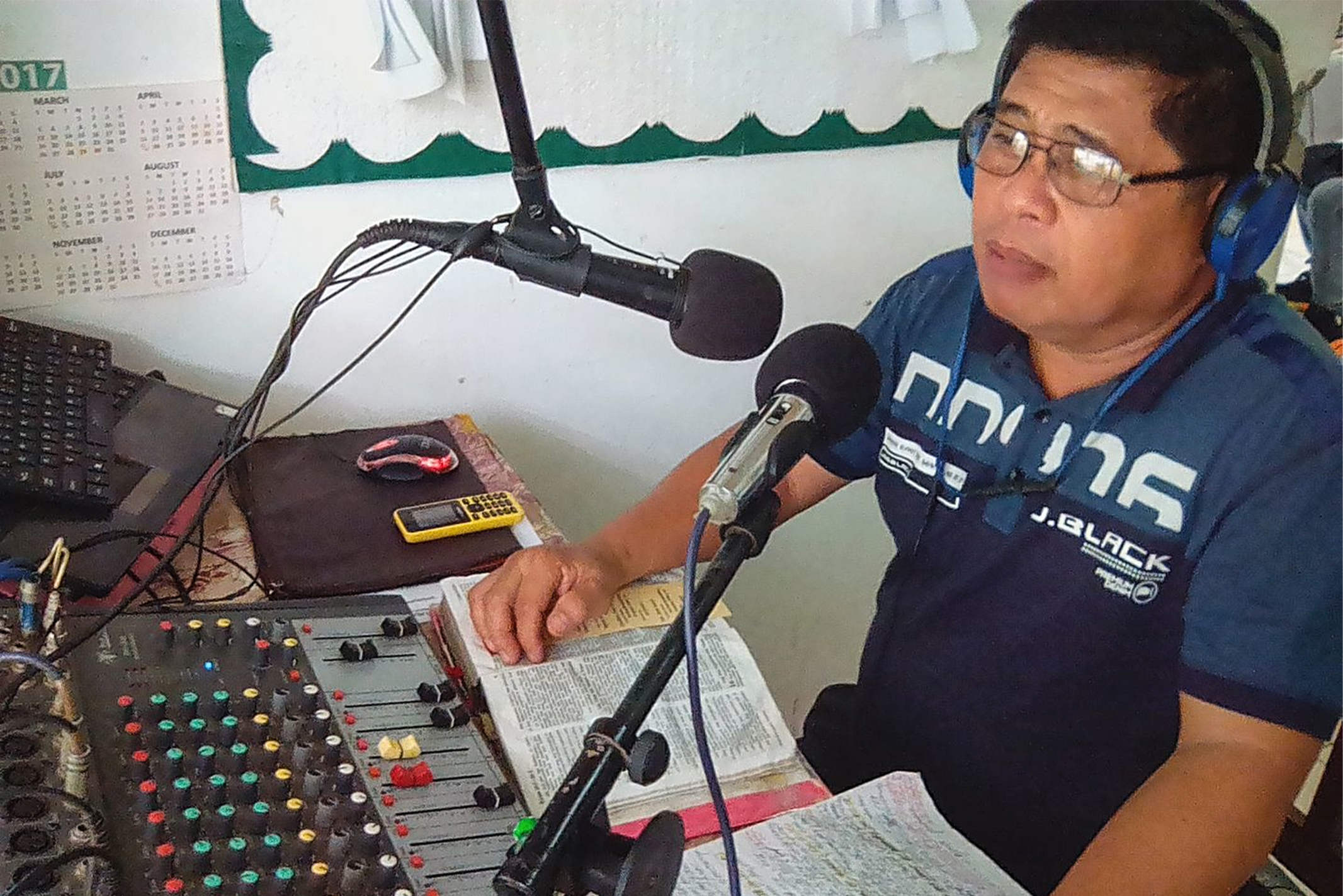 Cambodian man putting on a radio broadcast of the Bible