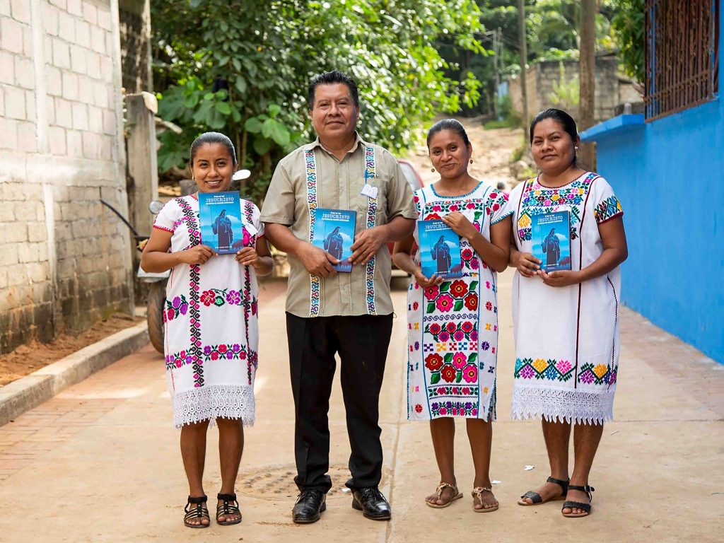Mexican Christian missionary standing on a street with three women each of them holding a book titled, "Jesucristo"