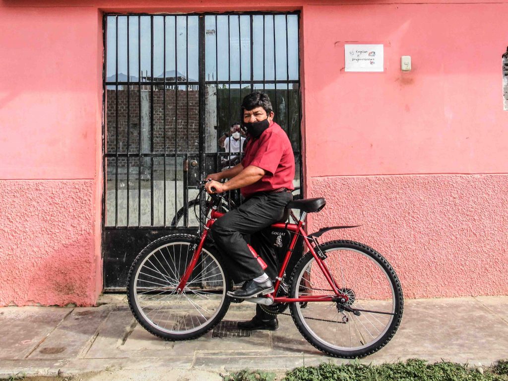 Latin American Christian missionary stopped on a sidewalk riding his red bike